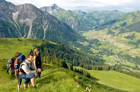 Hikers enjoying panoramic mountain view over alpine valley with villages below